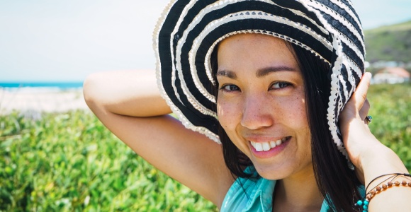 Asian woman under the sun with a hat but no sun glasses