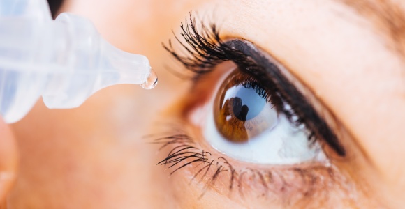 Woman putting eye drops in her eye